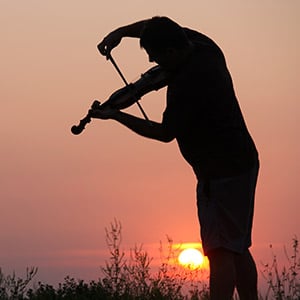 Man playing violin at sunset
