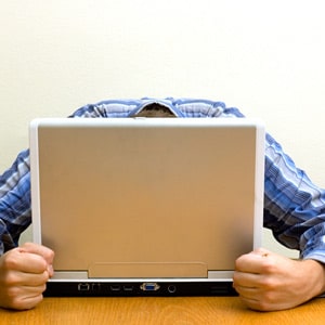 Frustrated man with head down behind laptop