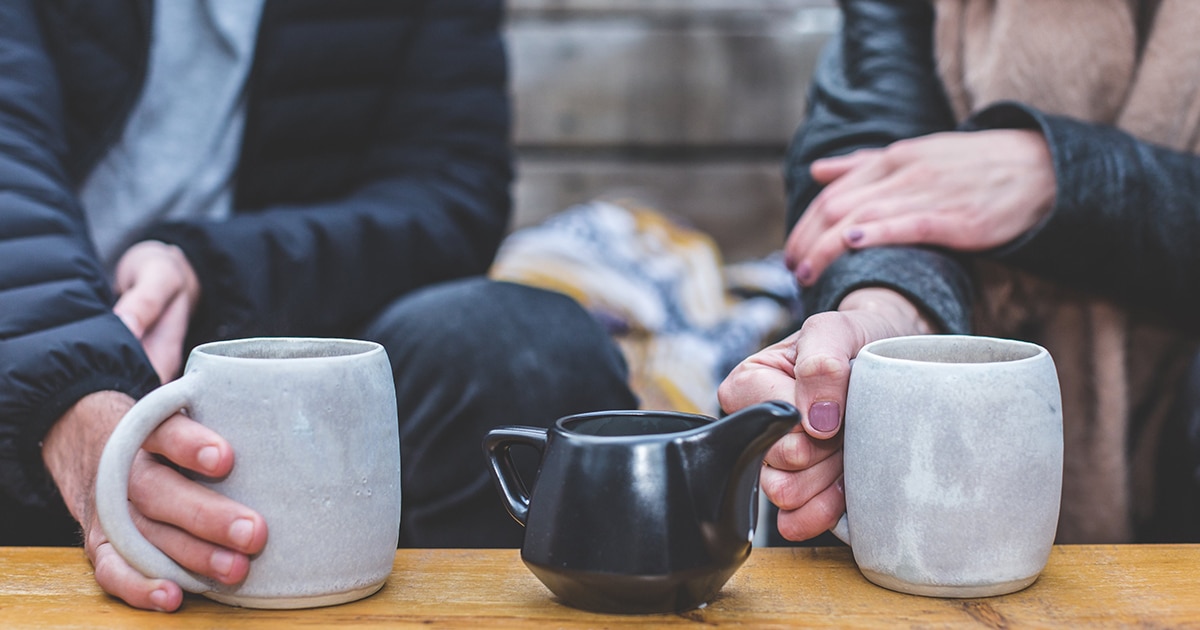 Two people talking over tea with teapot in between image