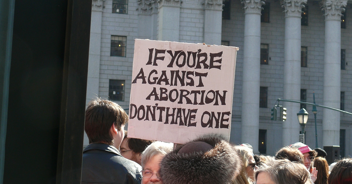 Man holding sign that says, "If you're against abortion, don't have one