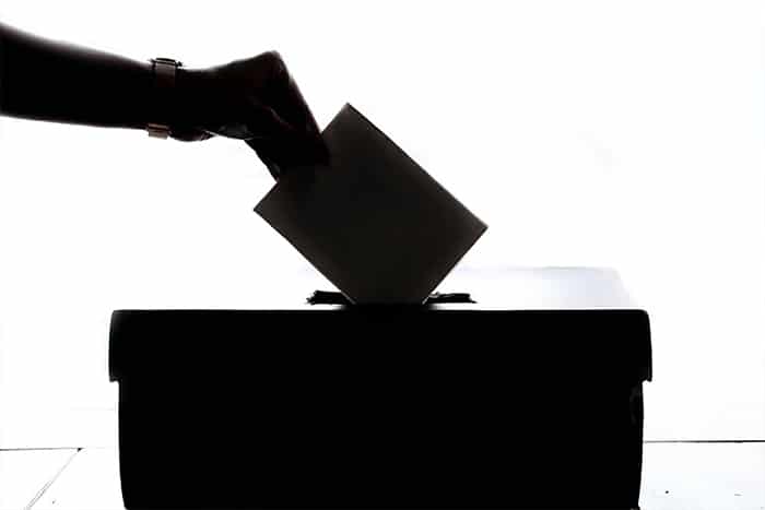 Hand placing a ballot into a ballot box